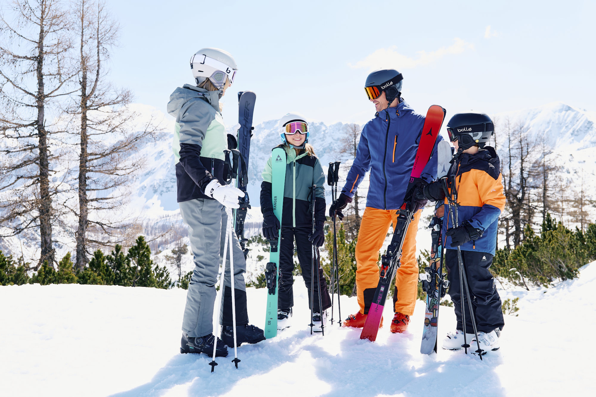 Eine Mutter, ein Vater und zwei Kinder stehen im Schnee, sehen sich an und haben Freude.