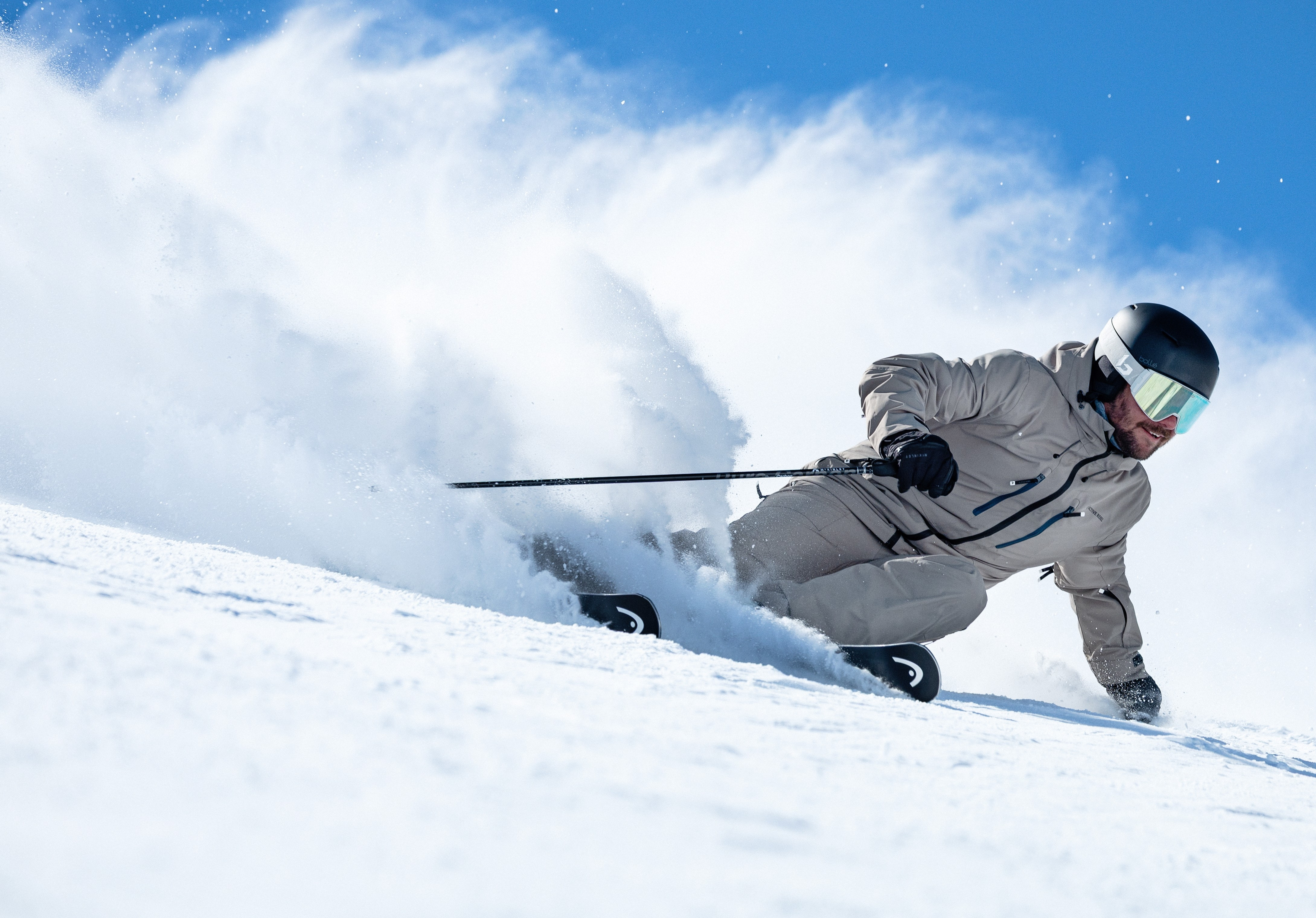 Skifahrer carvt an einem sonnigen Tag einen verschneiten Berghang hinunter. Wintersport und Freizeitaktivitäten im Freien.